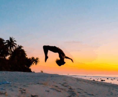 person doing a backflip against a sunset