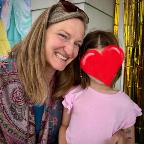 A woman next to a small girl with a heart covering her face